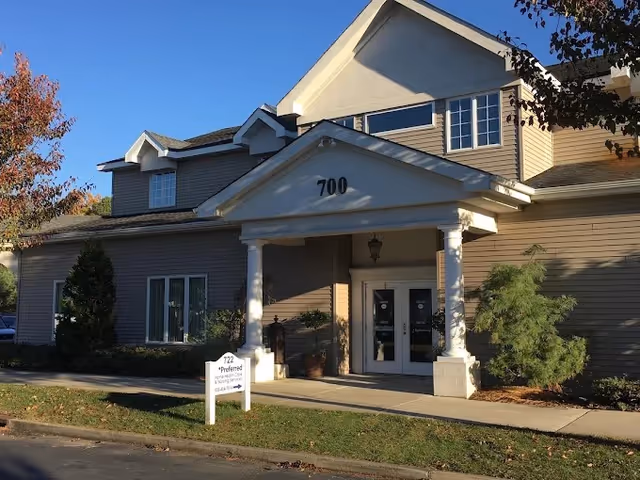 Exterior view of a two-story senior living facility entrance with address 700 and columns