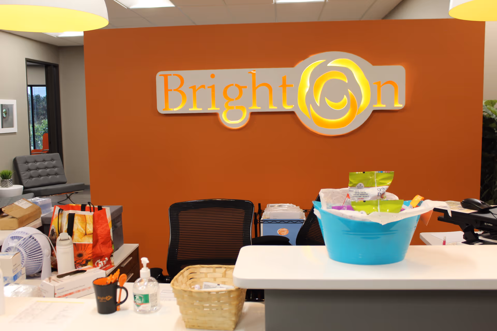 Reception area with orange wall and bright Brighton logo behind a desk