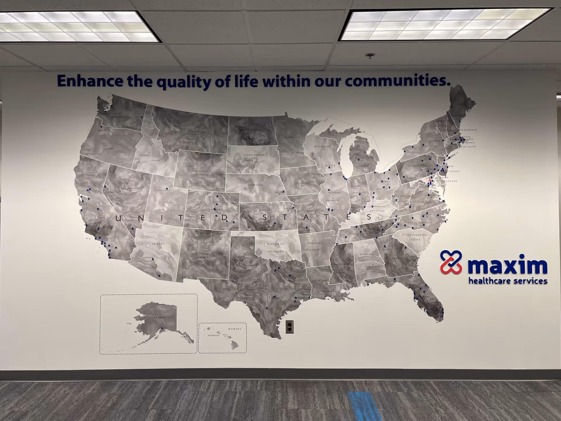 Large gray map of the United States on a wall beside the Maxim Healthcare logo.