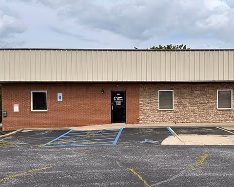 Front of a brick building with a door and handicapped parking spaces.