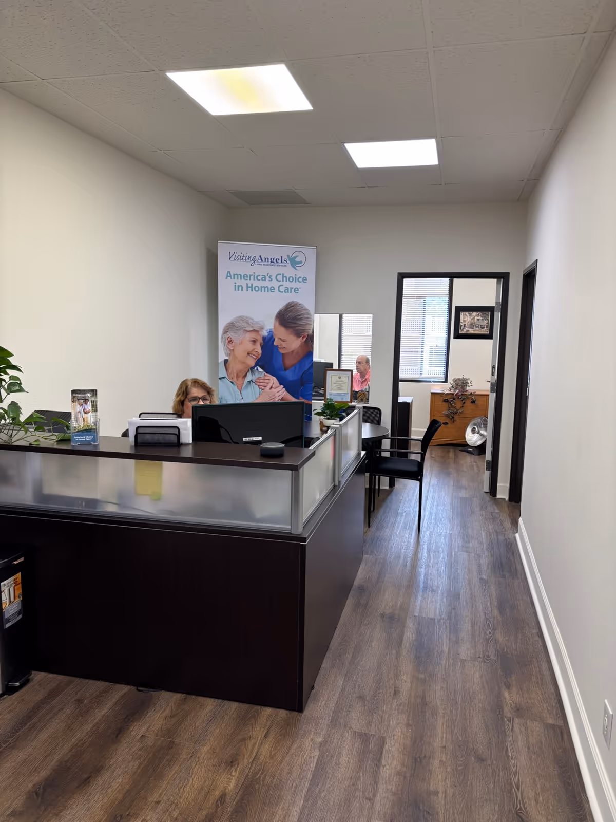 Reception desk in Visiting Angels home care lobby with banner and office equipment