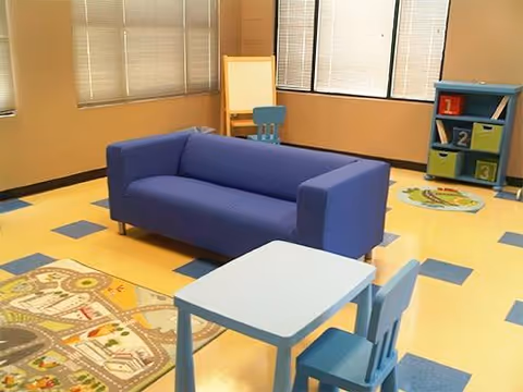 Interior play area with blue couch, small table and chairs, toy storage.
