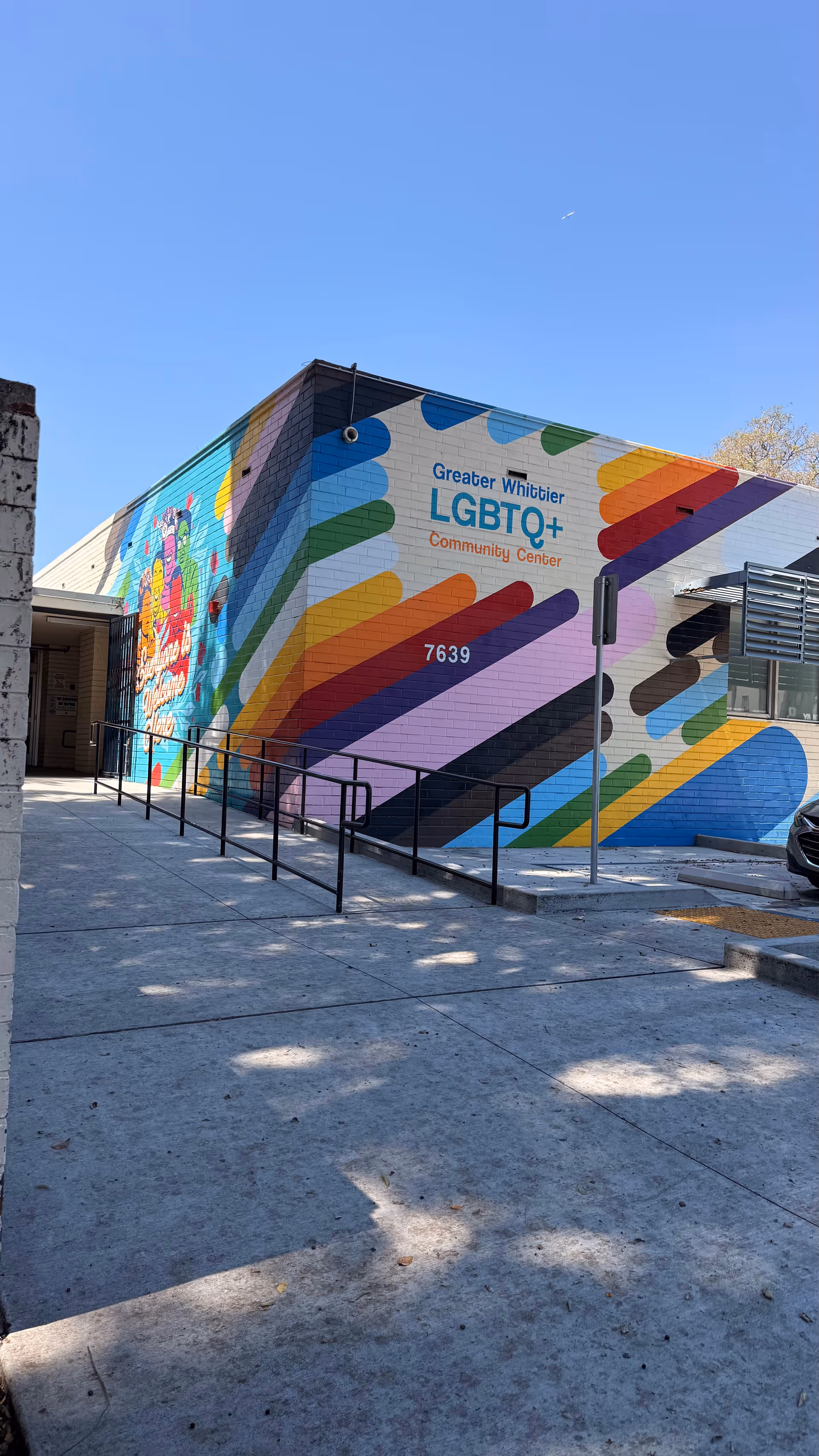 A bright mural covers the building exterior, featuring rainbow shapes and a ramped walkway.