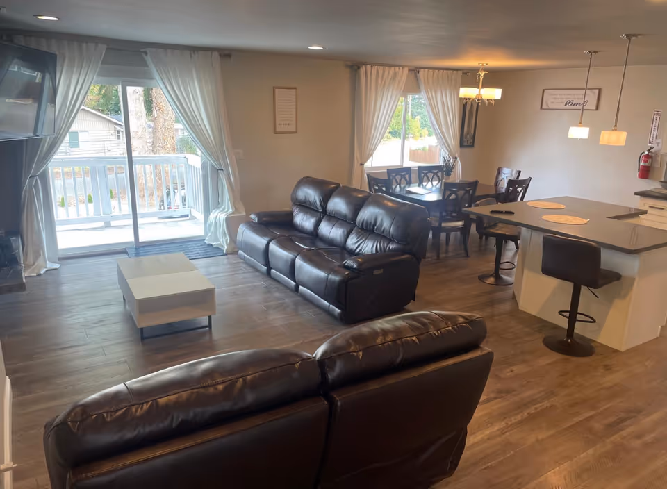 Open-concept living area with leather sofas, a dining table, and a kitchen island.