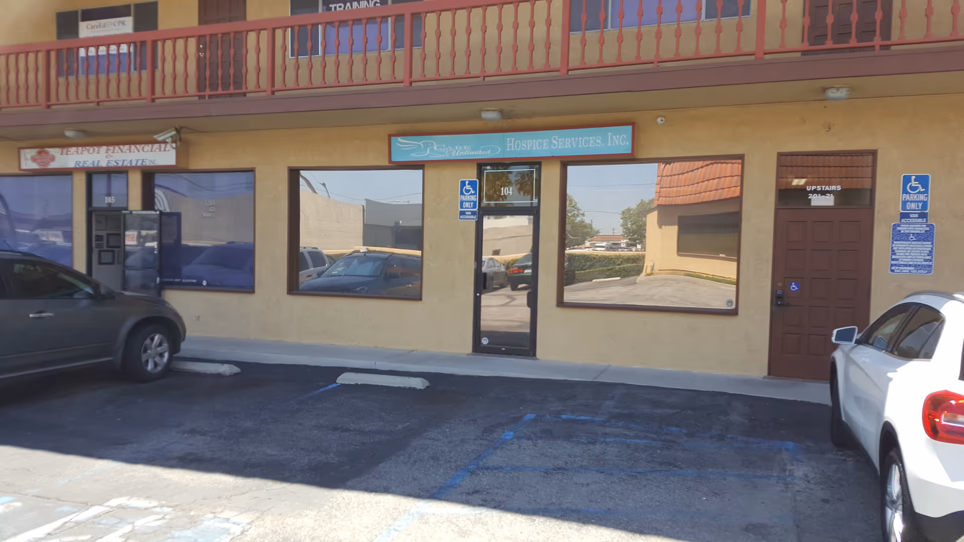Exterior view of a beige, single-story building with storefront windows and a wheelchair sign