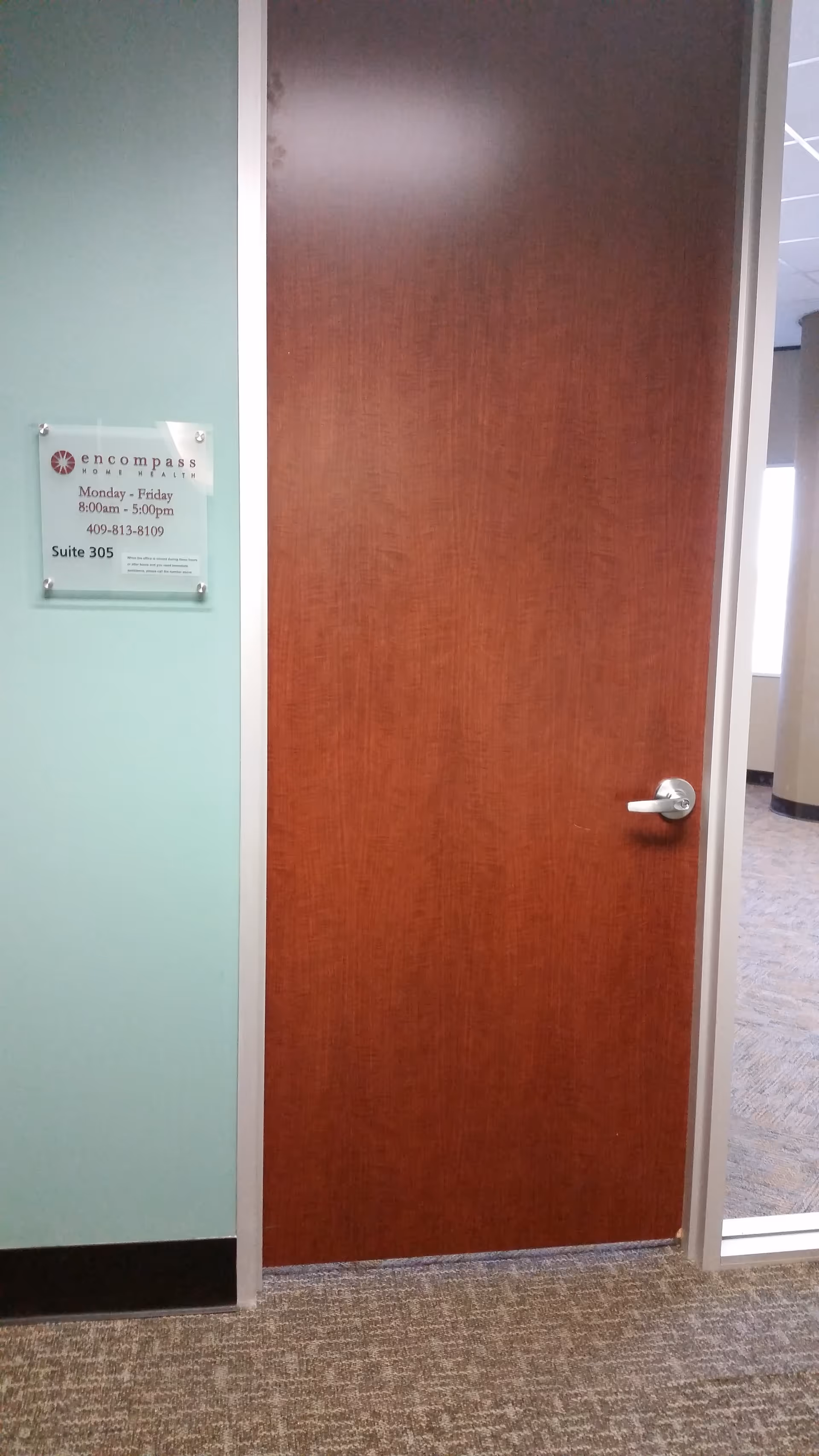 Wooden interior door in a hallway with a mint-green wall and a sign