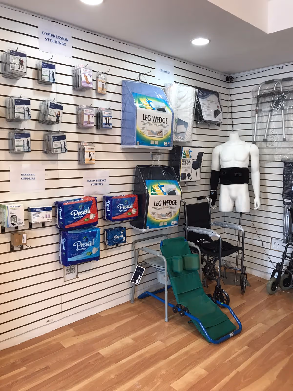 Interior showroom displaying medical supplies, leg wedges, walkers, and a torso mannequin.
