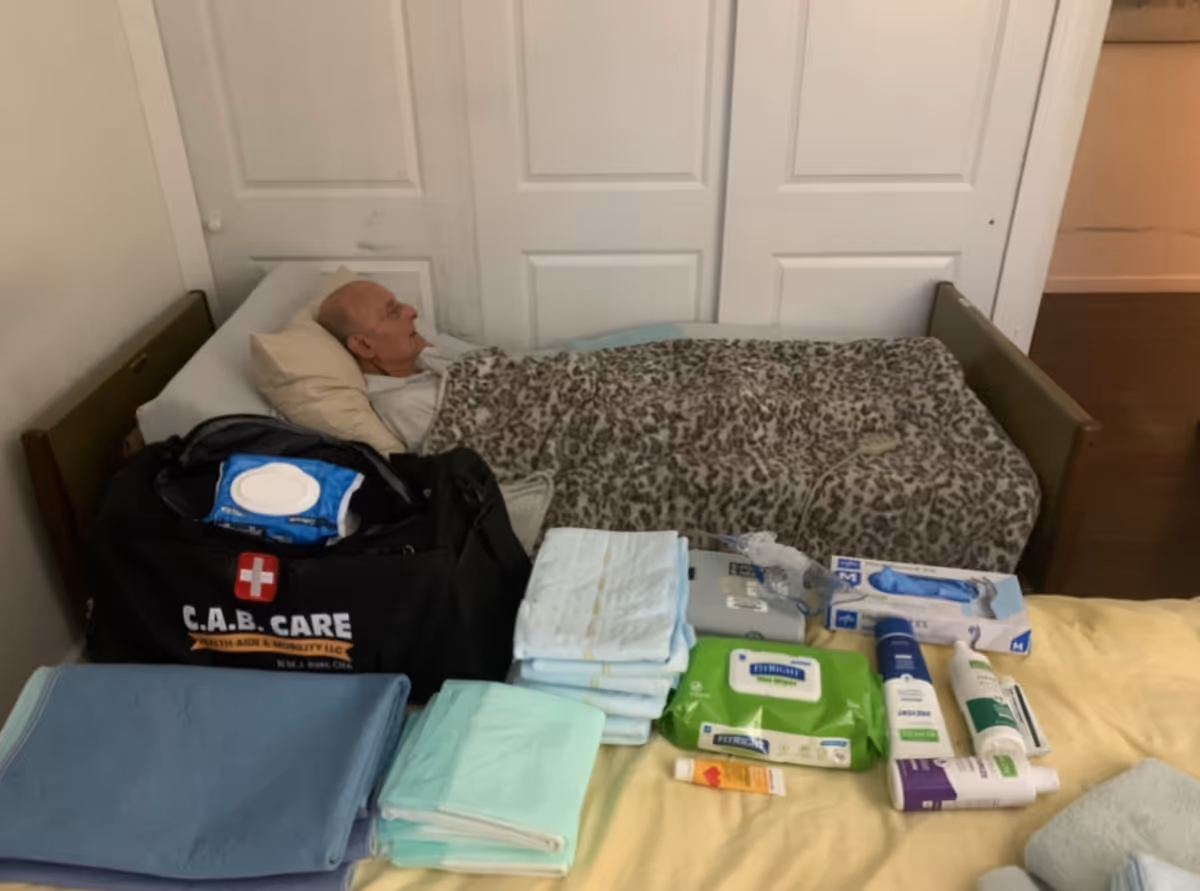 Elderly man lying in bed with a care bag and medical supplies nearby