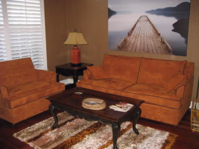 Orange sofa set, coffee table, lamp, and wall art in a cozy living room.