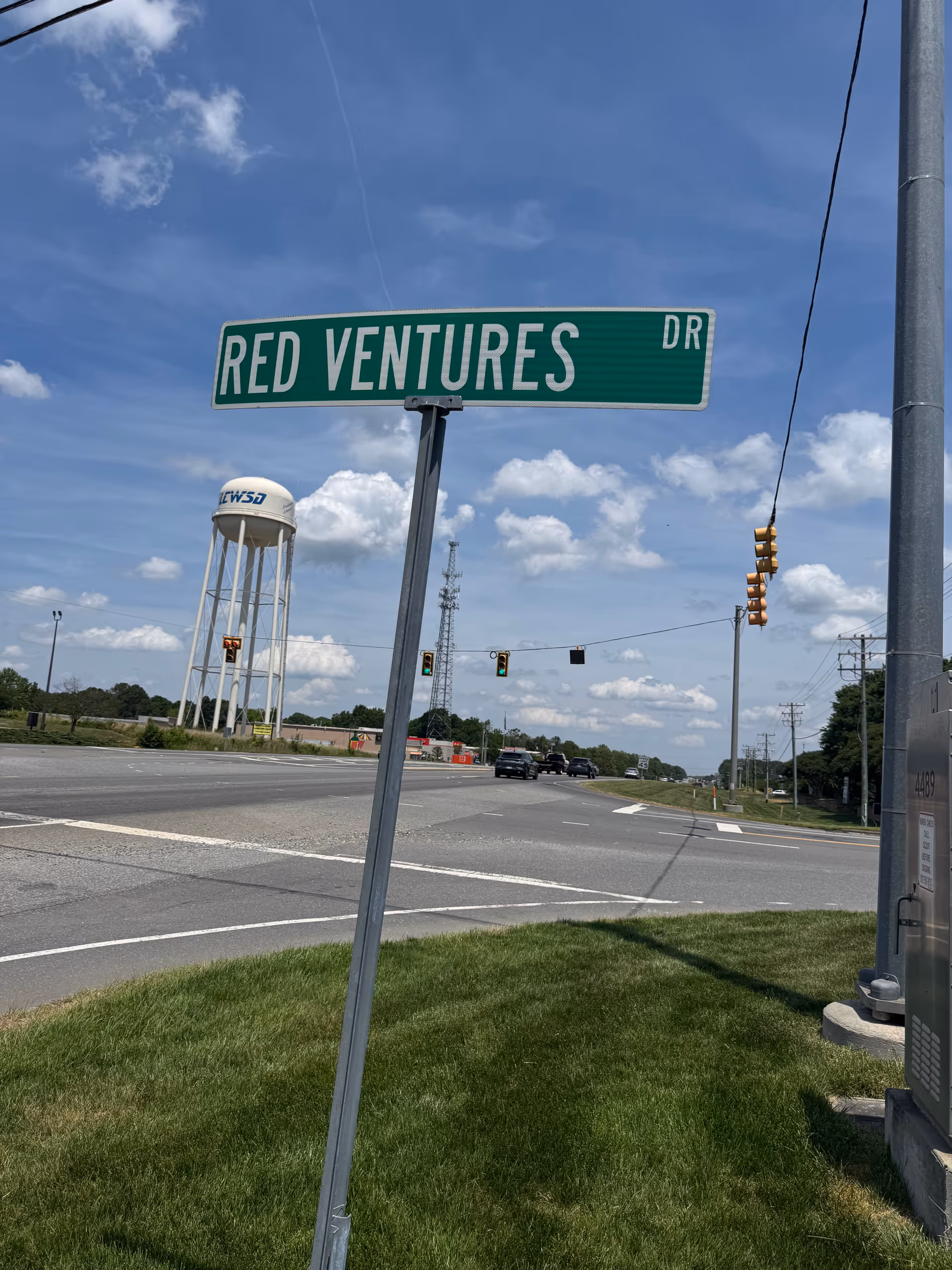 Tilted street sign reading Red Ventures Dr under a bright blue sky.