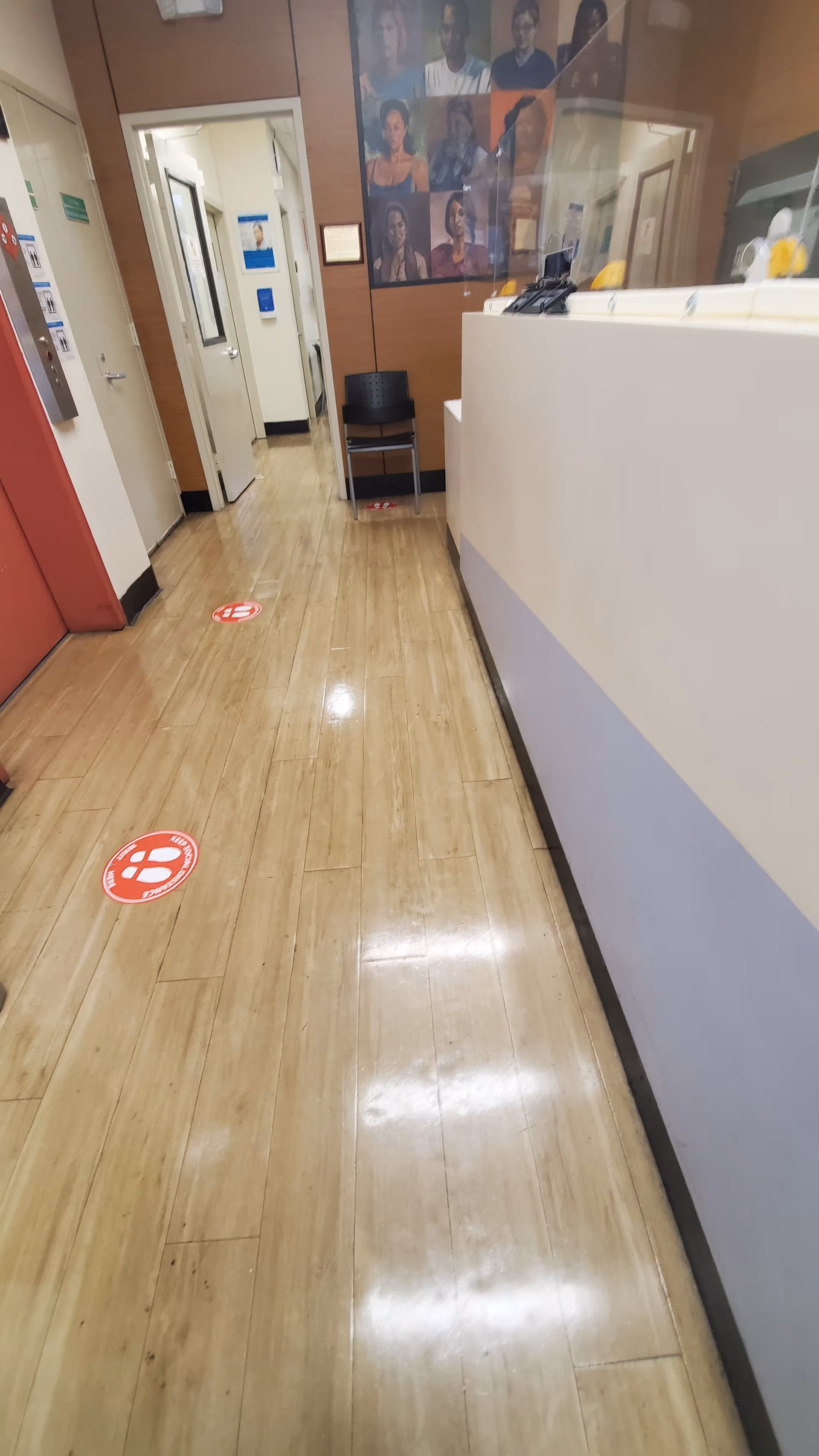 Interior hallway of Community Healthcare Network Crown Heights with a reception desk and wall portraits.