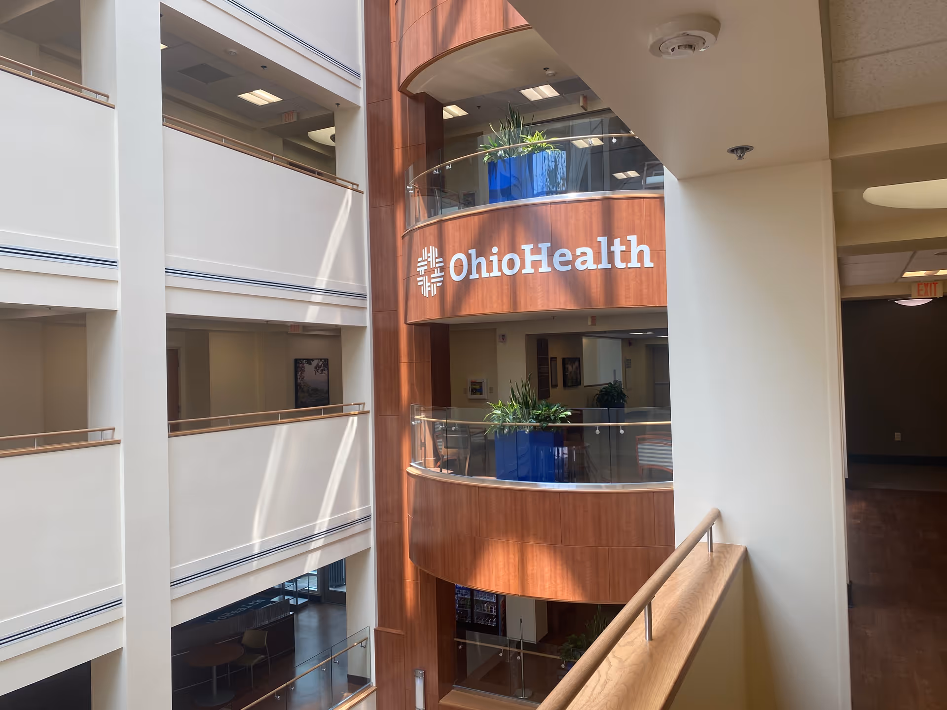 Multi-story indoor atrium with glass balconies and a curved wood wall labeled OhioHealth