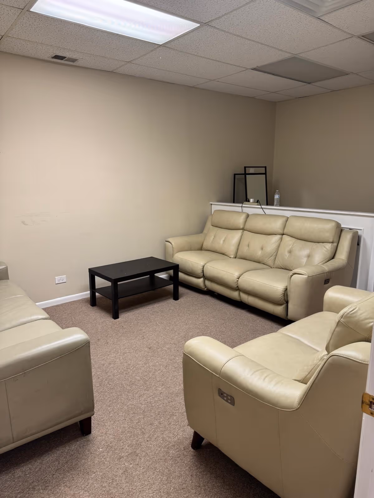 A beige lounge with leather sofas and a small black coffee table.