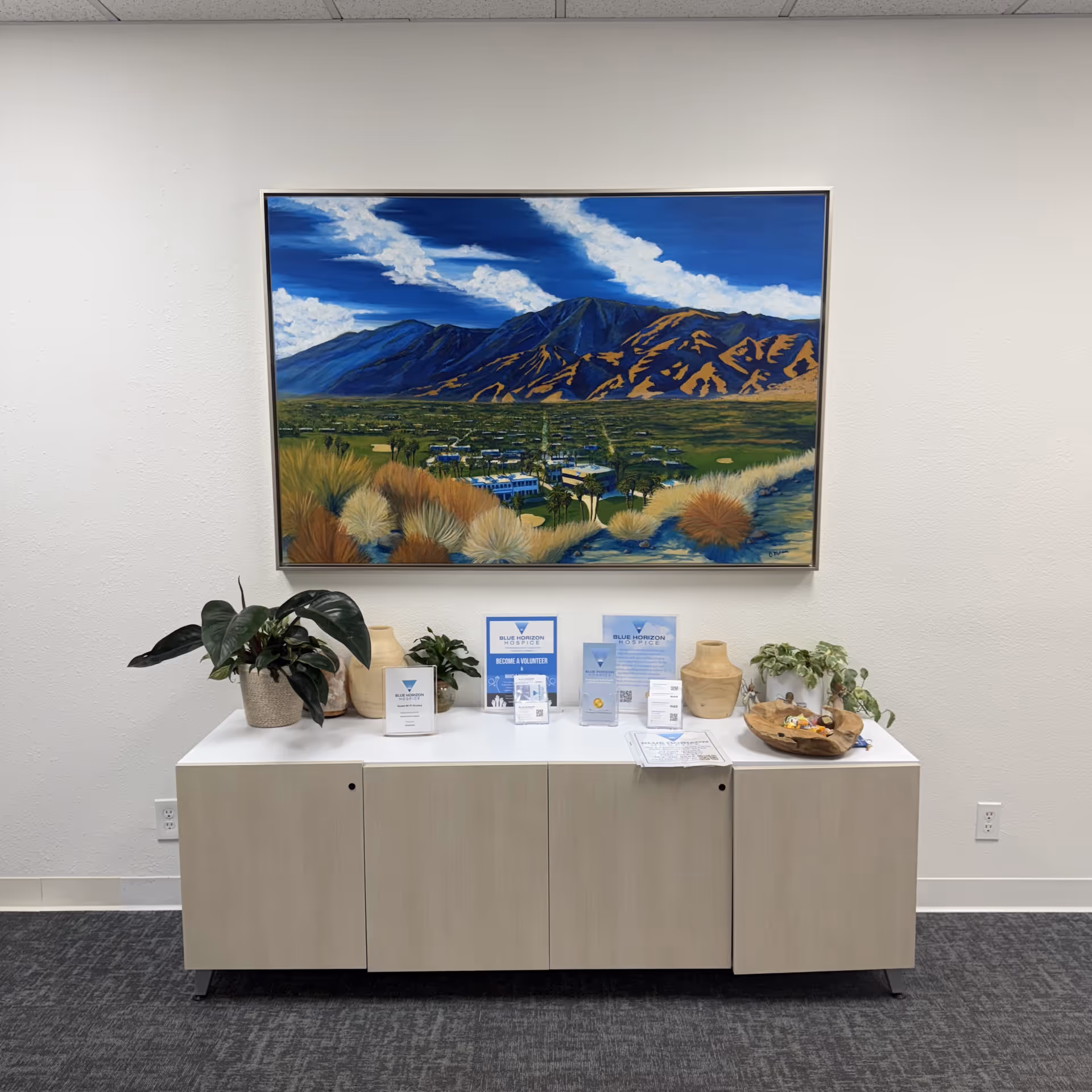 Lobby interior with a large landscape painting above a white cabinet and brochures.