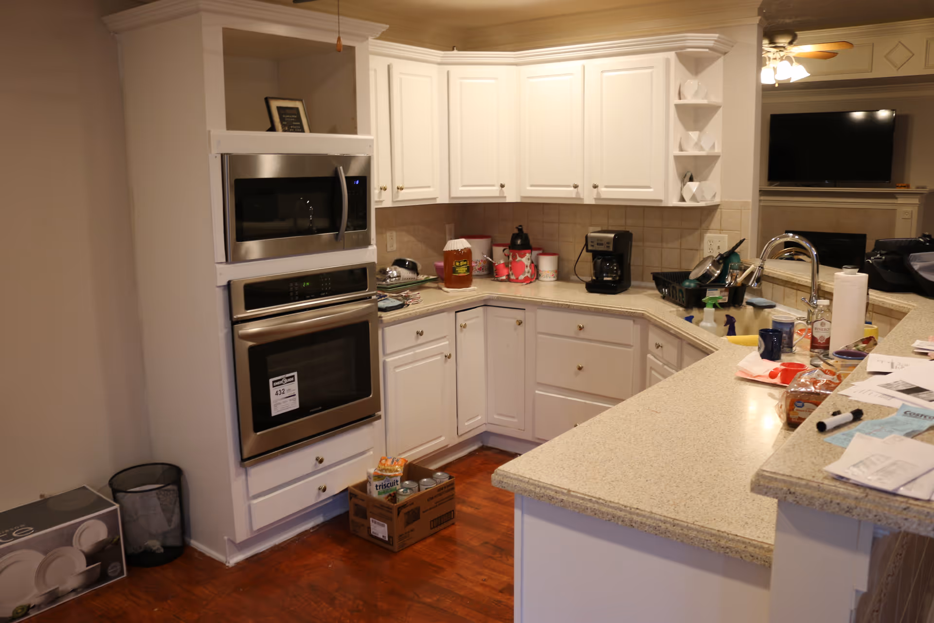 Bright white kitchen with built-in ovens, cabinets, and a granite island.