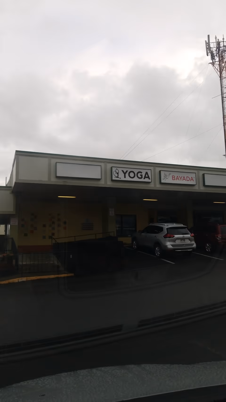 Exterior view of a BAYADA Home Health storefront with a Yoga sign and parked cars.