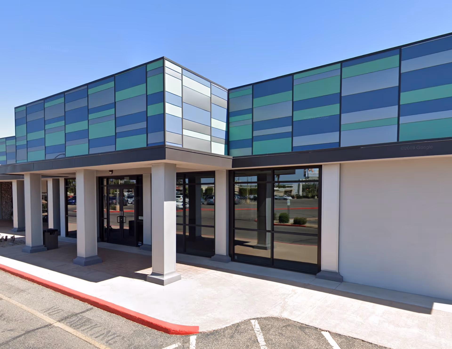 Exterior view of a modern building with colorful paneling and glass entrance.