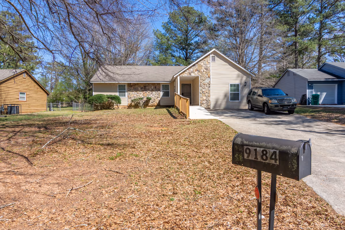 Single-story facility with stone facade, driveway, and a black mailbox numbered 9184.