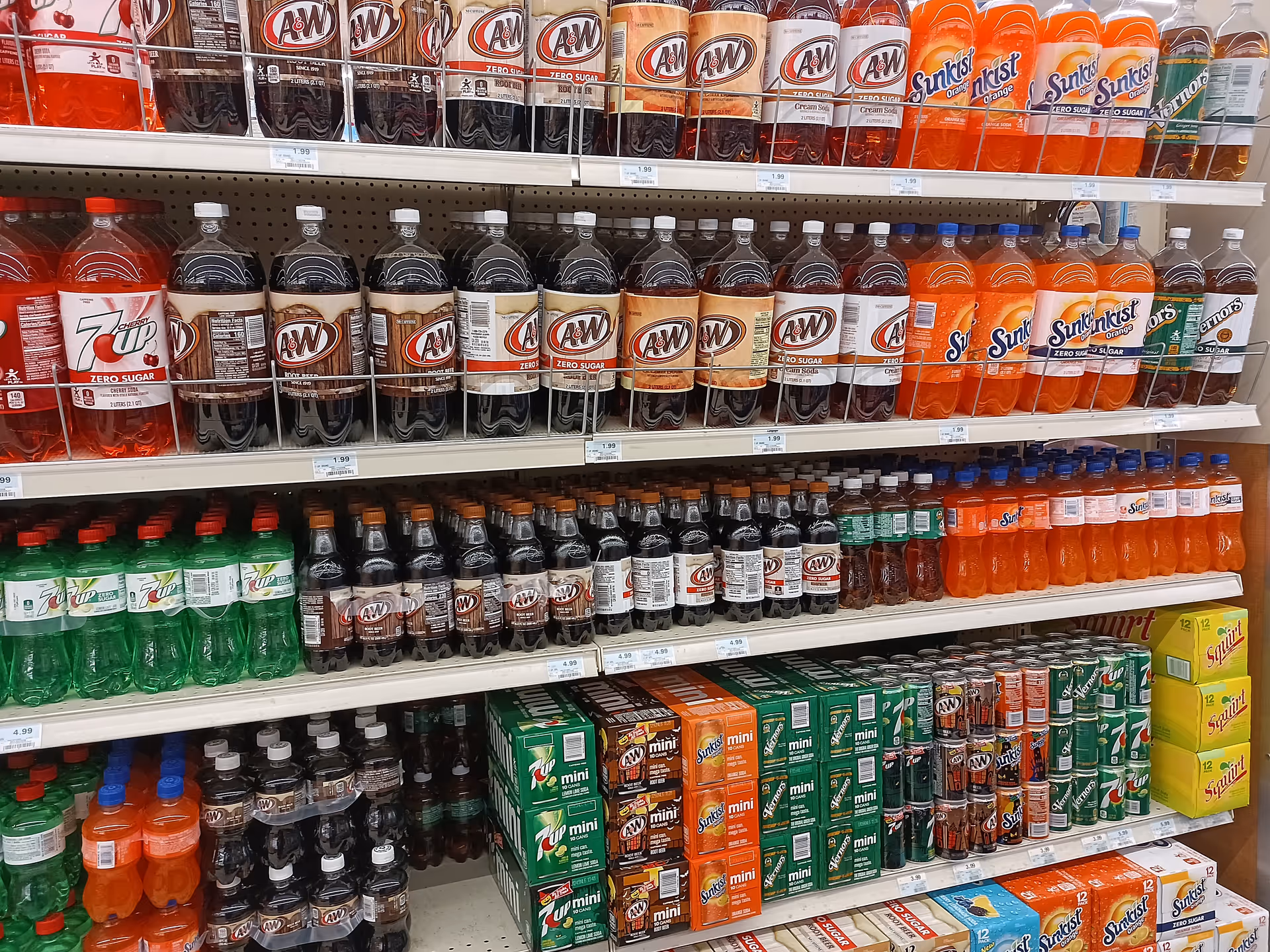 Aisle of assorted sodas and beverages on grocery store shelves.