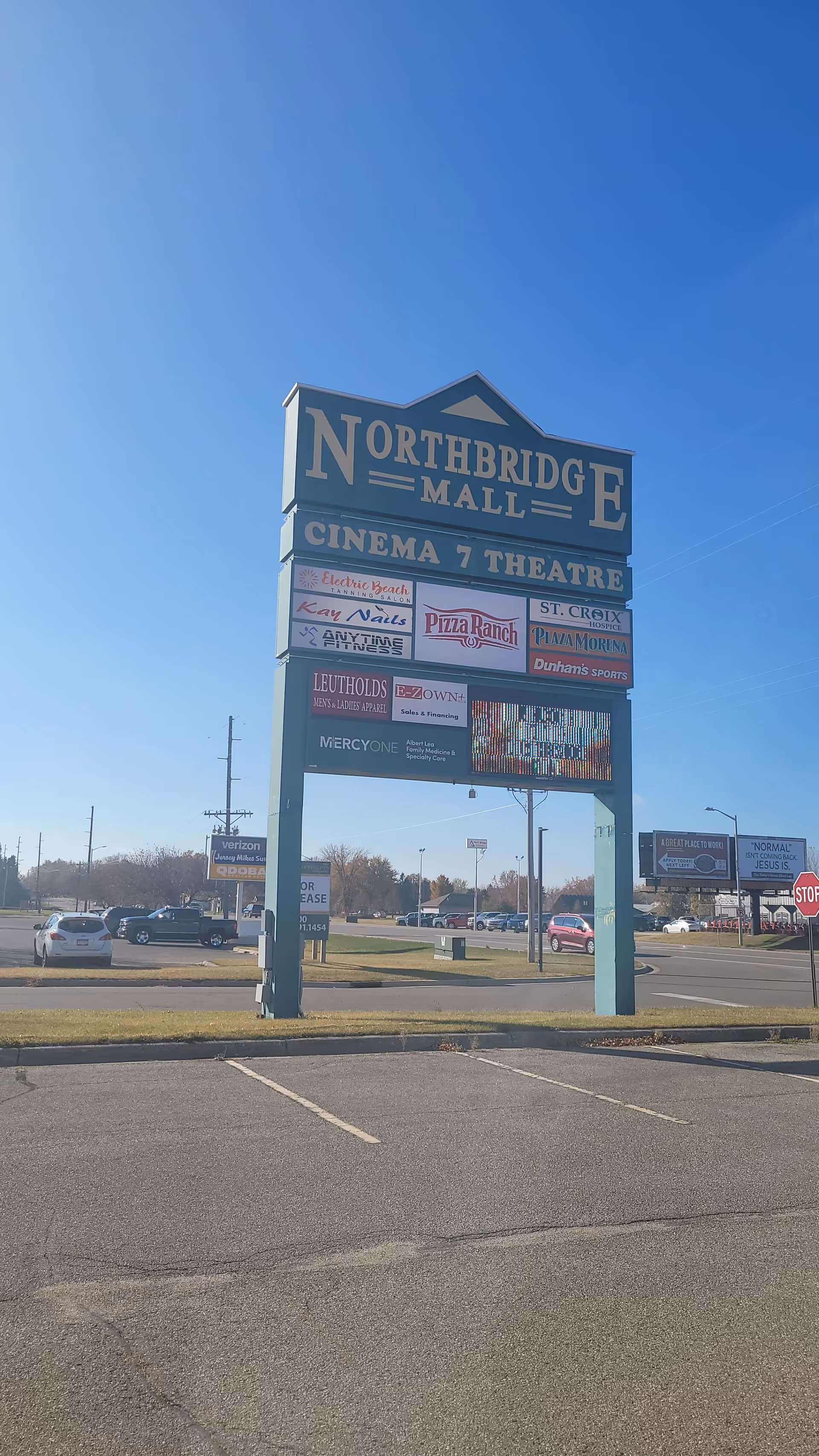 Tall blue mall sign reading Northbridge Mall with shops and parked cars.