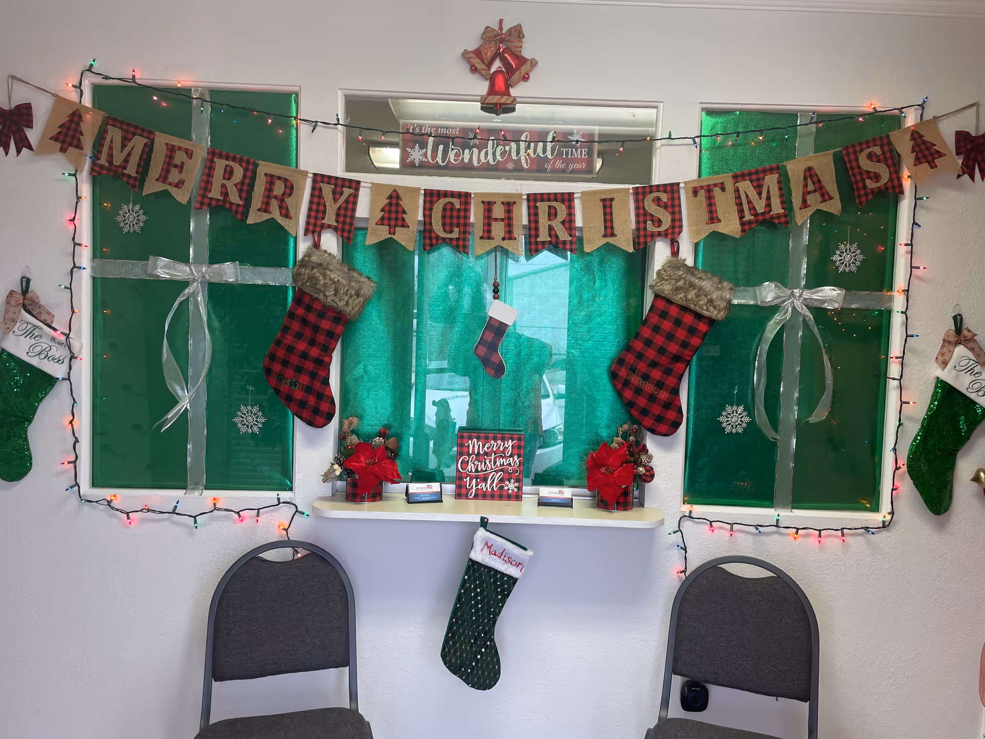 Festive Christmas decorations, banners, stockings, and lights decorate a senior living facility common area.
