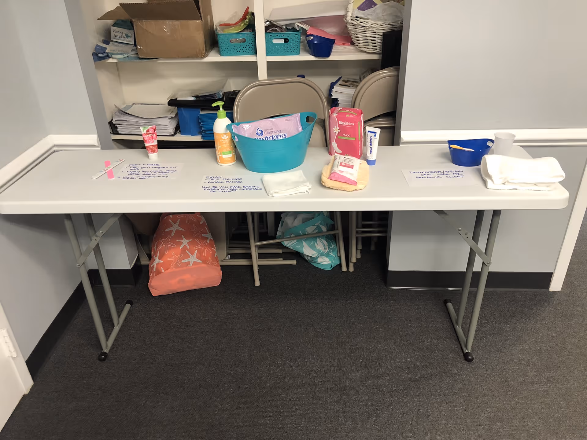 A long folding table with cleaning supplies inside a senior care facility supply room.
