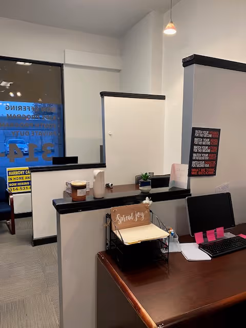 Reception desk with clutter, computer, and mail rack inside Harmony Care in Home & CDS