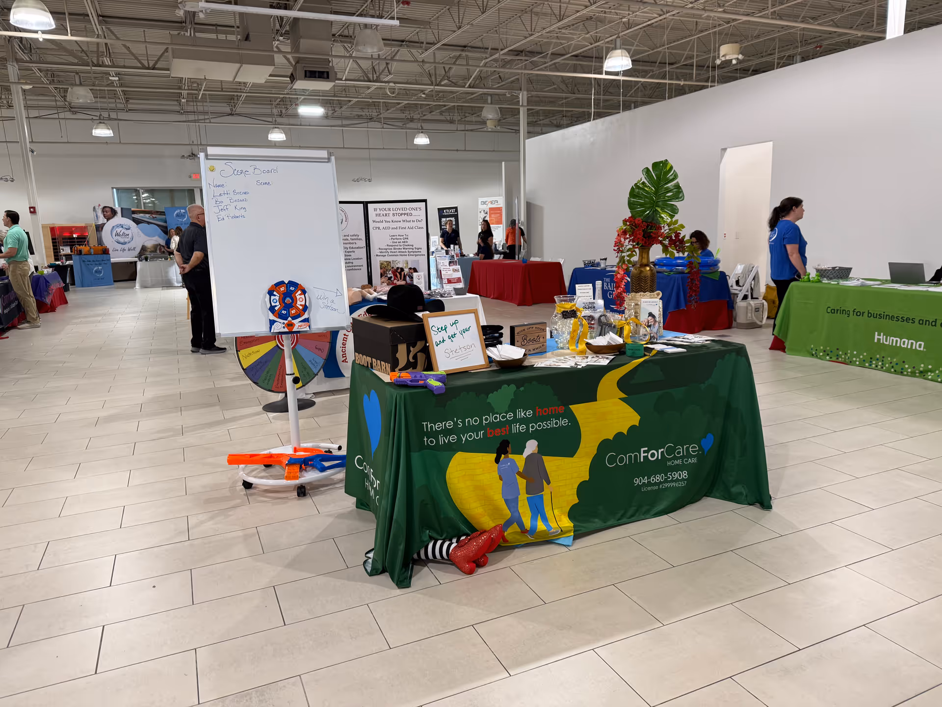 Indoor trade show booth for ComForCare Home Care with a colorful banner and wheel.