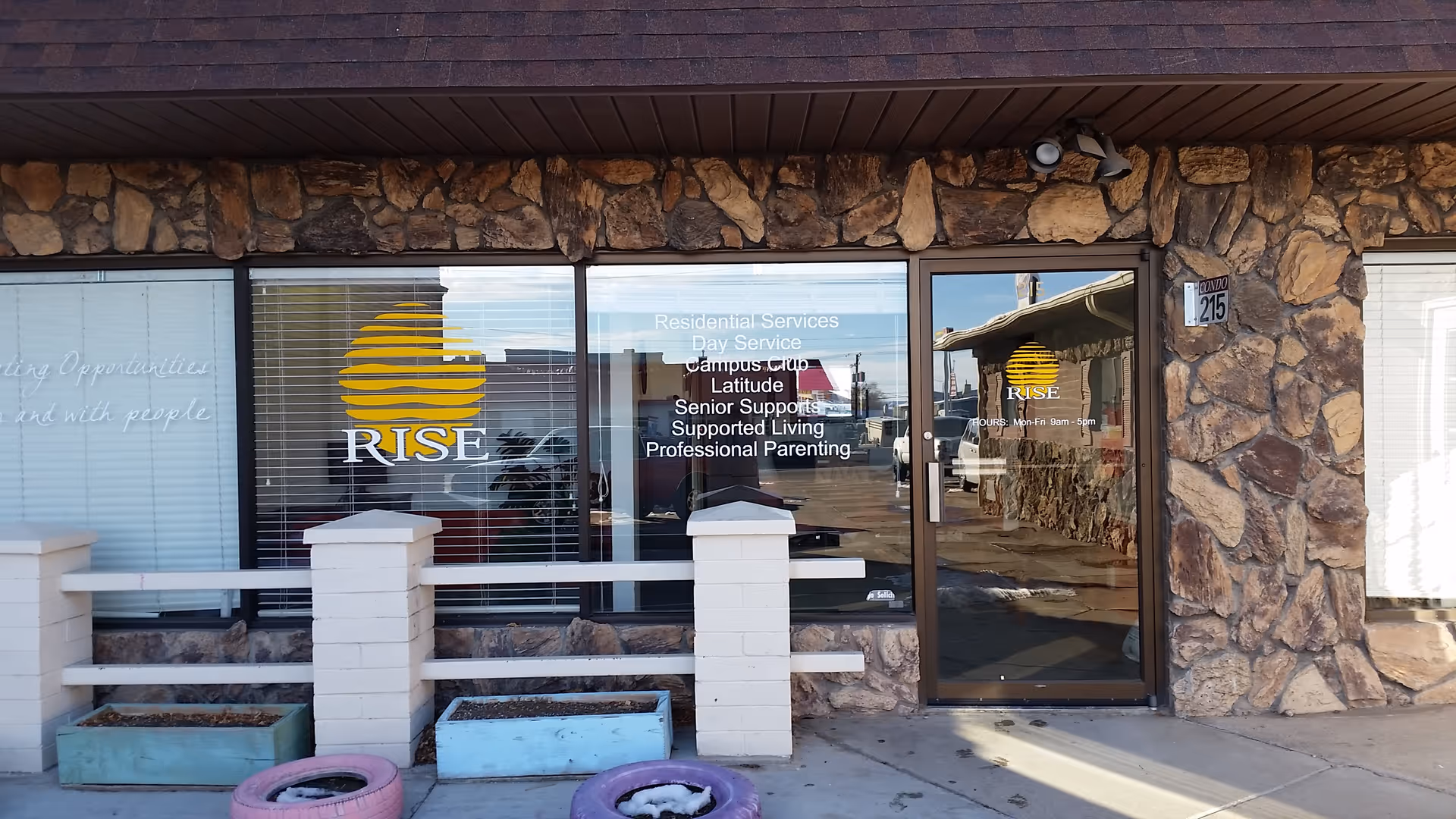 Stone-front building entrance labeled RISE Services with logo window and glass door.