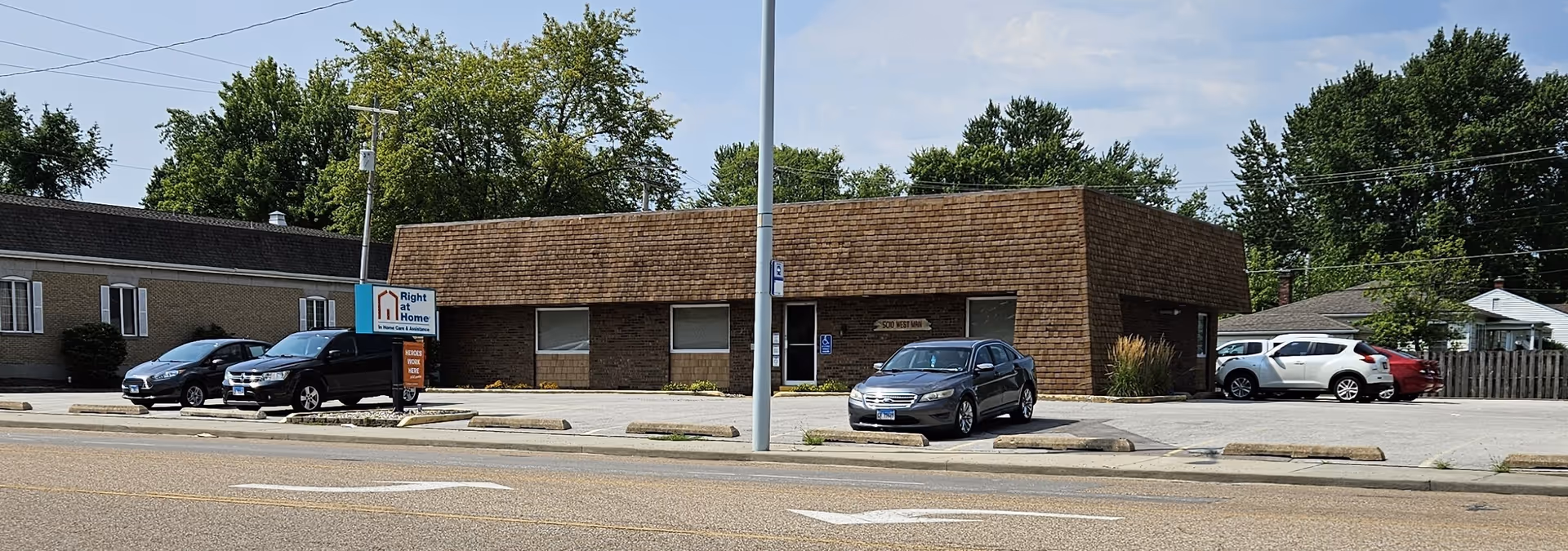 Exterior view of a Right at Home senior living facility with cars parked in front.