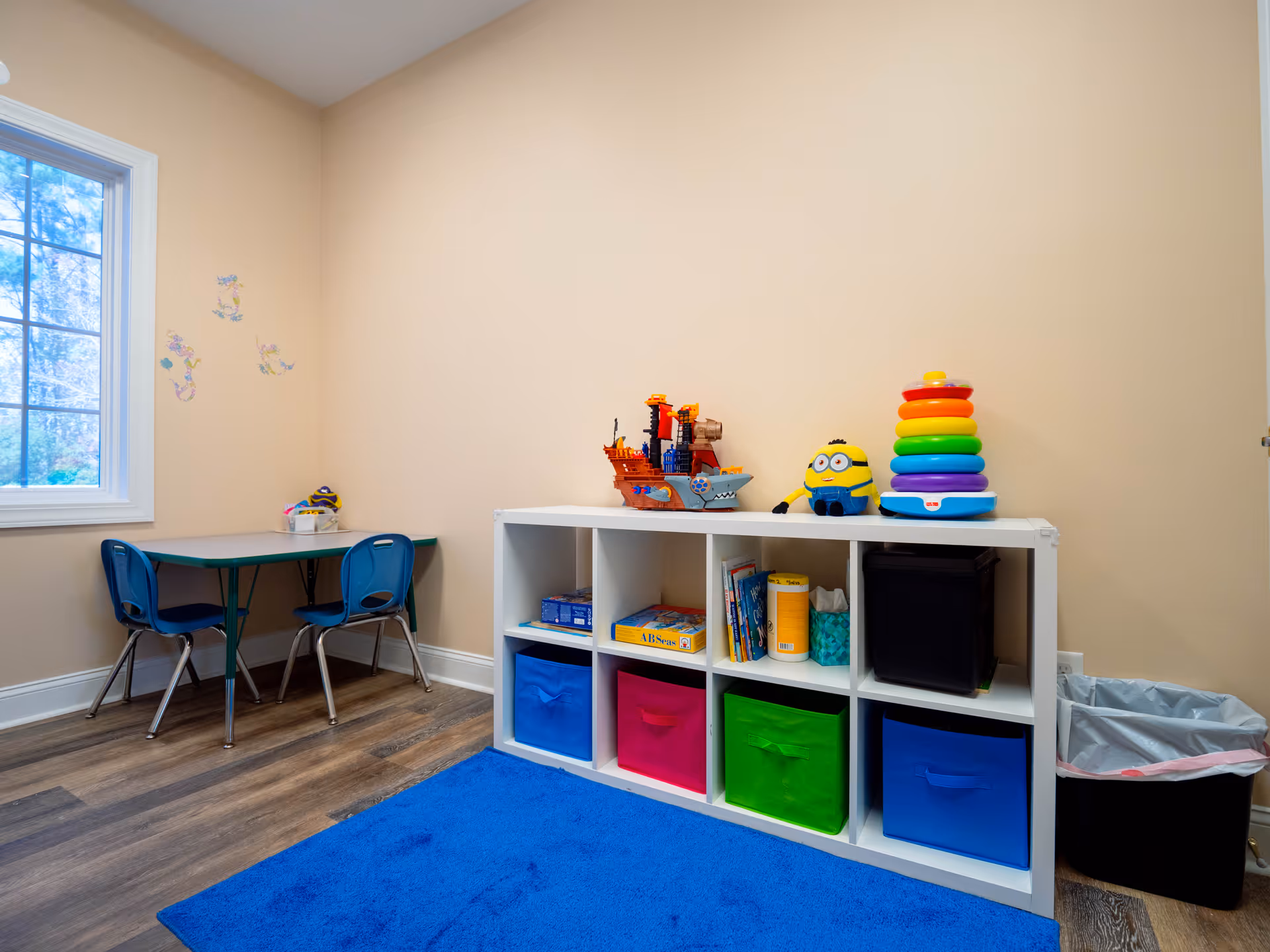 Playroom corner with cubby storage, colorful bins, and toys on a low table.