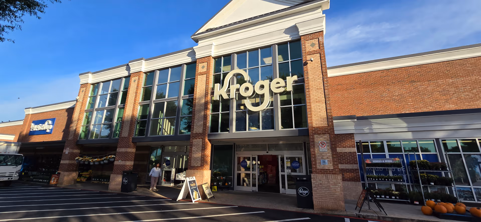 Wide view of Kroger storefront with brick facade and large glass entrance.