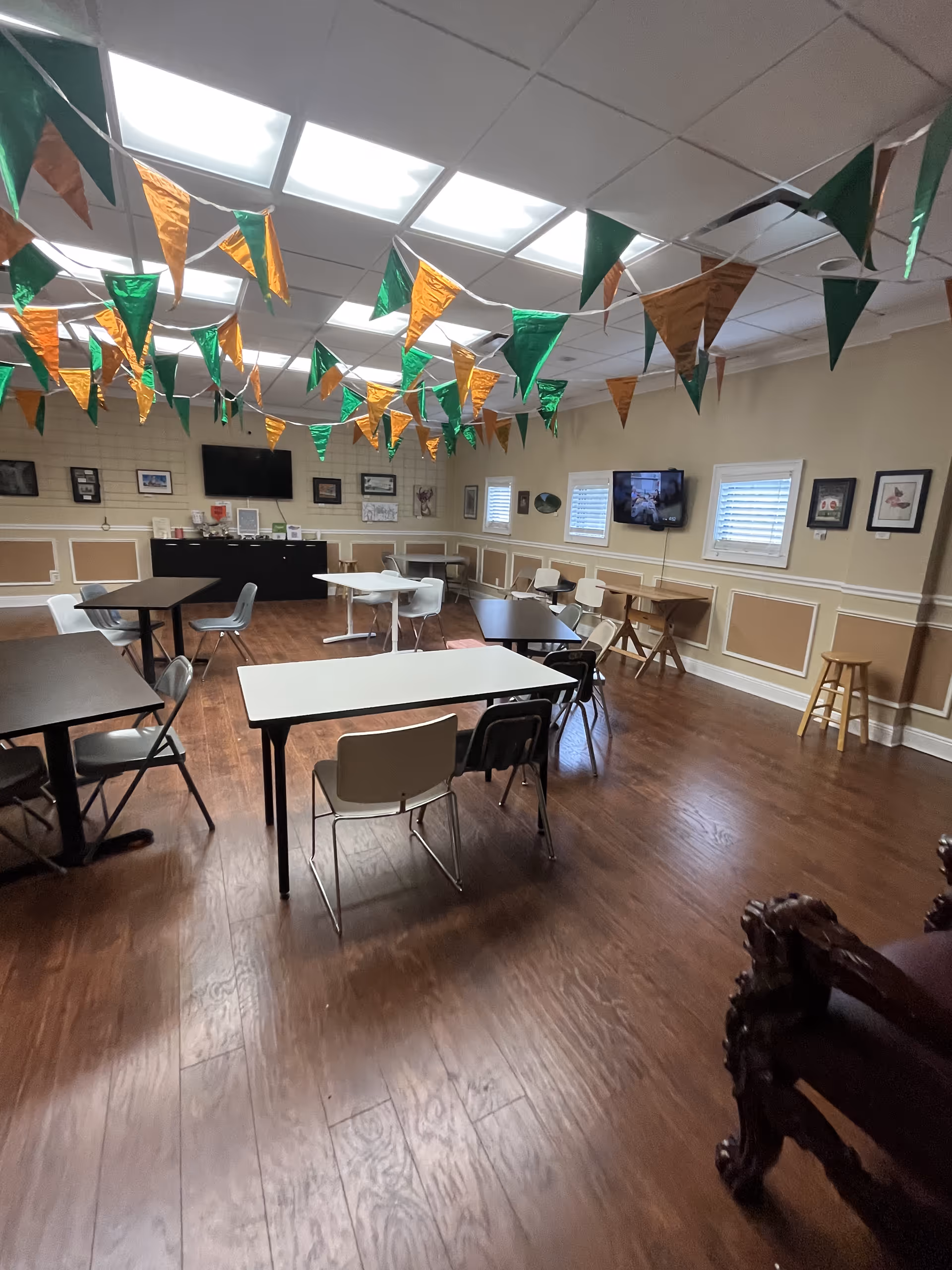Indoor common room with tables, chairs, and festive bunting in a senior living facility.