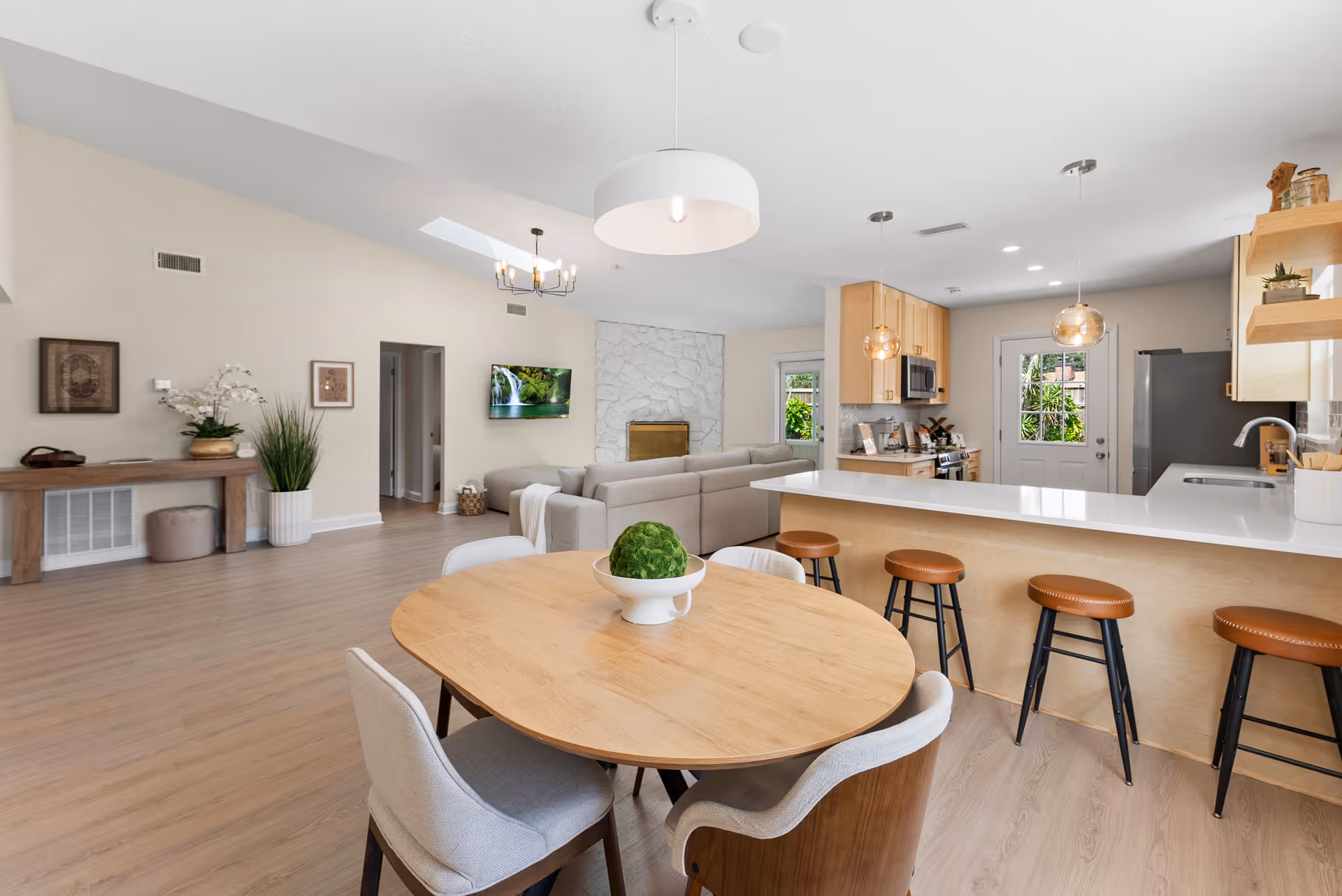 Open-concept senior living area featuring a dining table, kitchen island, and gray sofa.