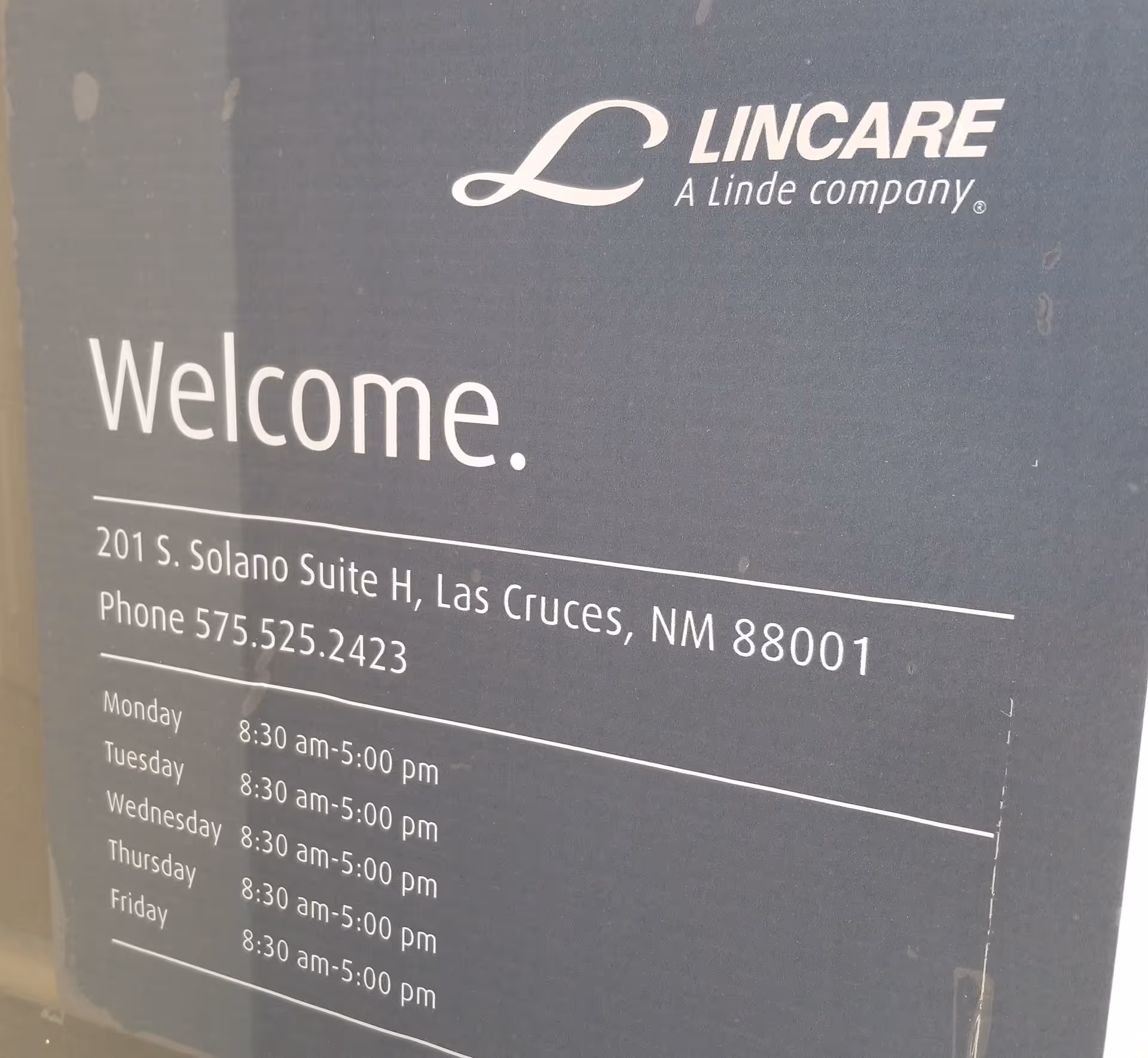 Close-up of a LINCARE welcome sign with address and hours.