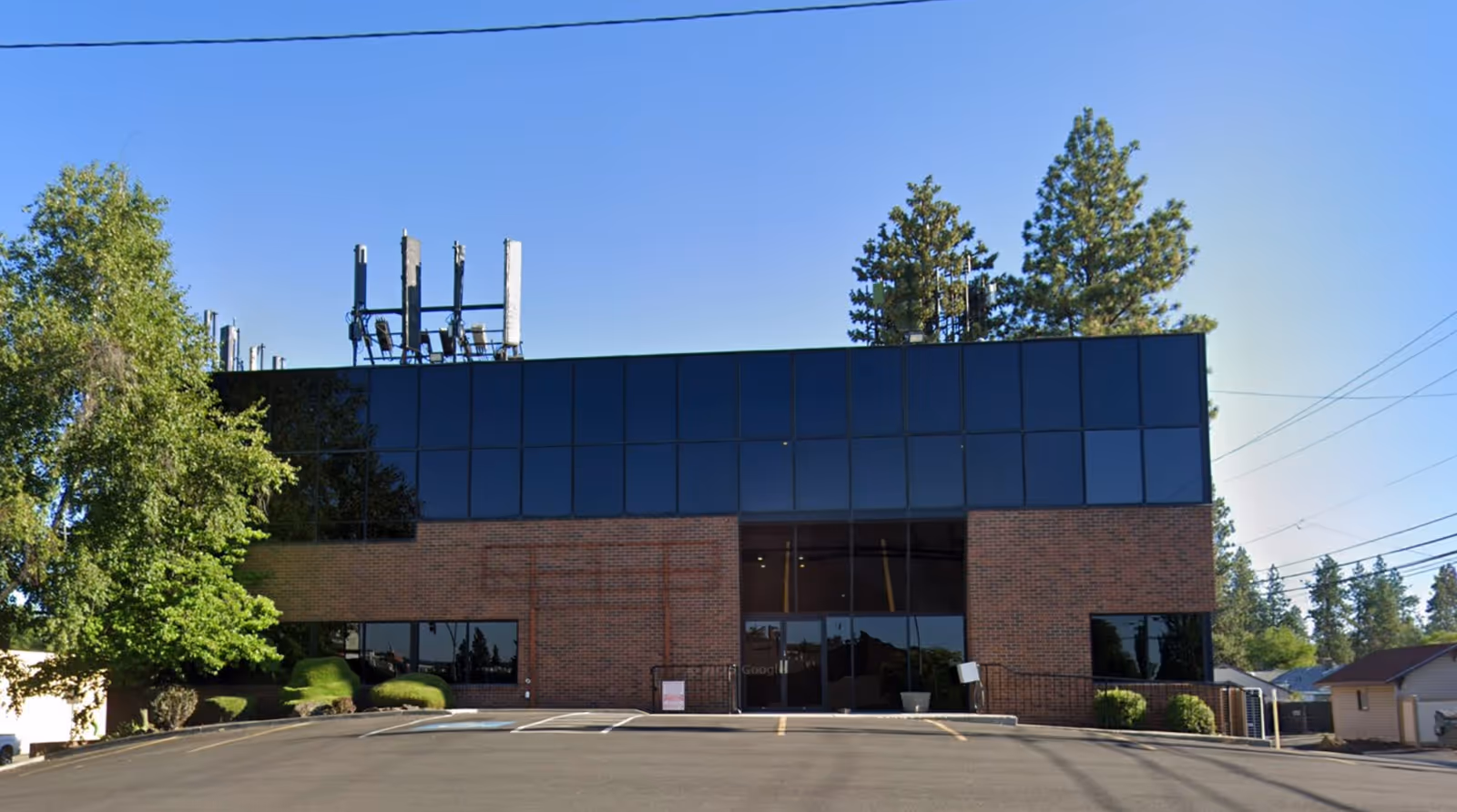 Front view of a brick-and-glass building with large windows and surrounding trees.