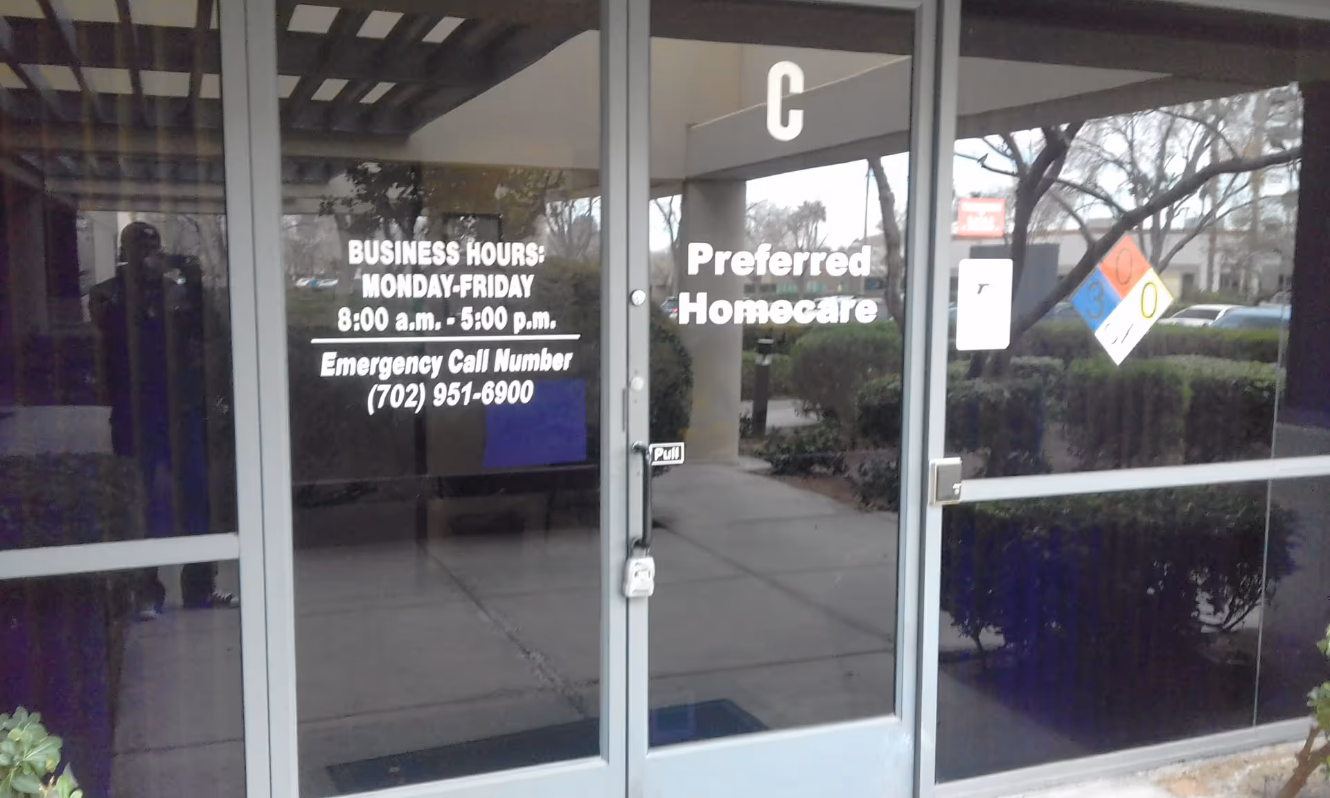 Glass doors display Preferred Homecare with hours and emergency contact