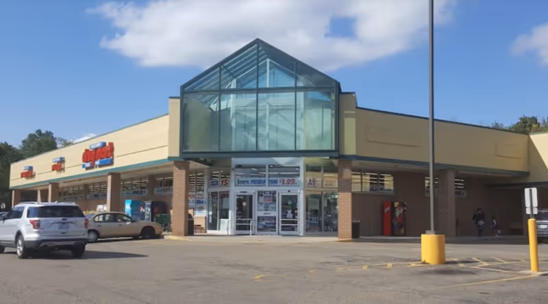 Exterior view of Discount Drug Mart storefront with glass atrium and parking lot