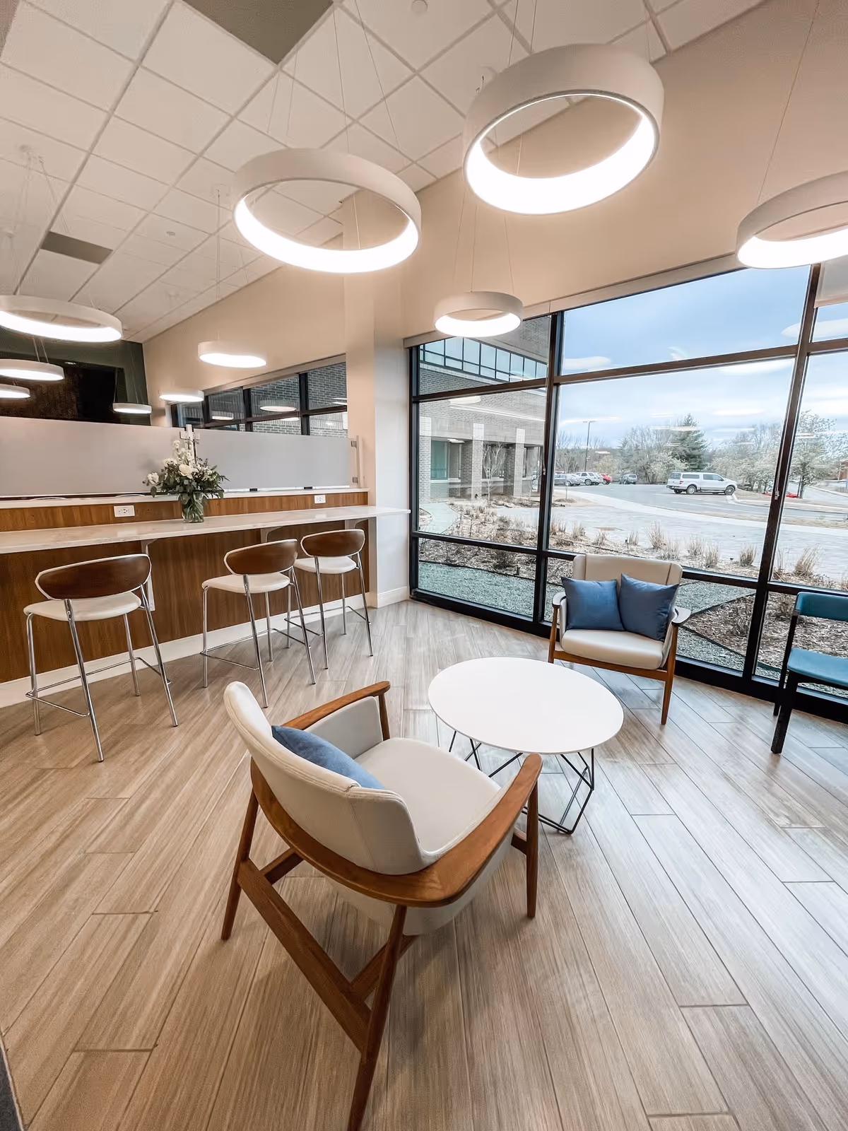Modern senior living lounge with circular pendant lights, a high counter, and cozy seating.