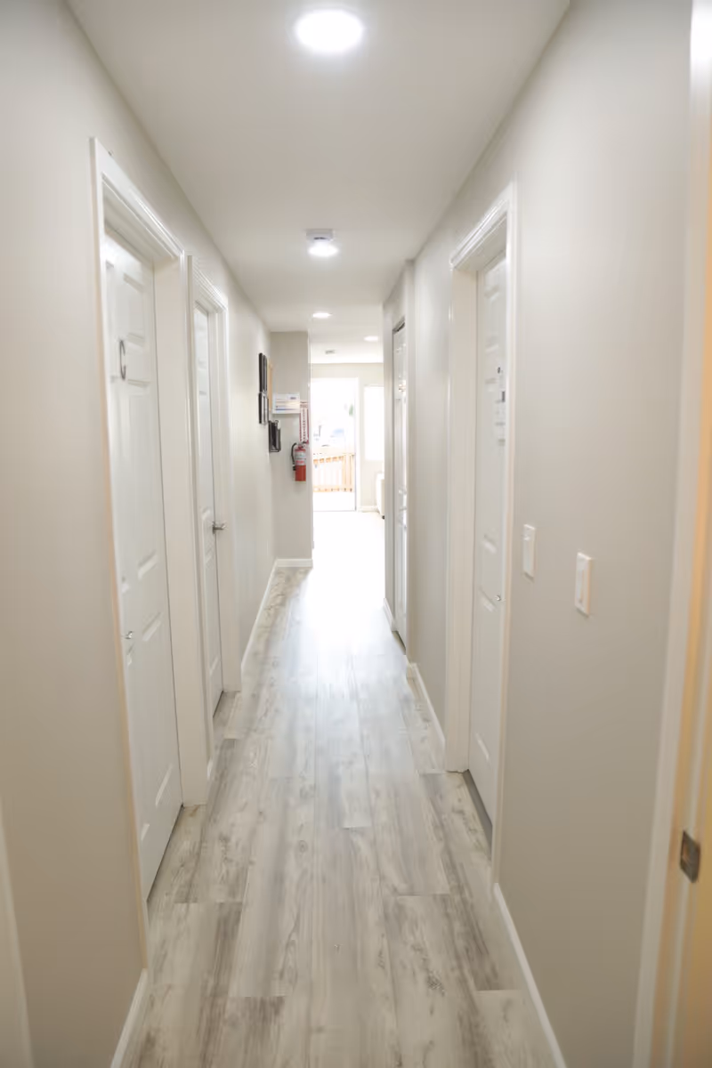 Bright, clean hallway inside a senior living facility with multiple doors.