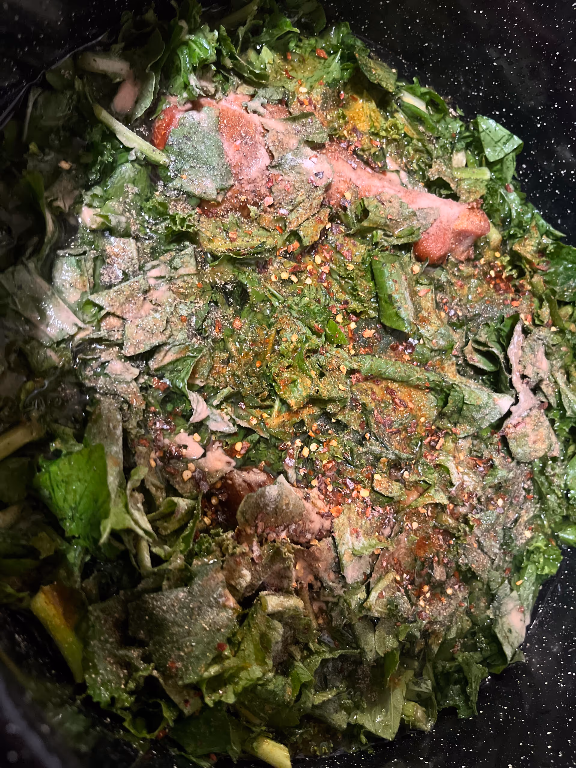 Chopped leafy greens with spices in a cooking pot.