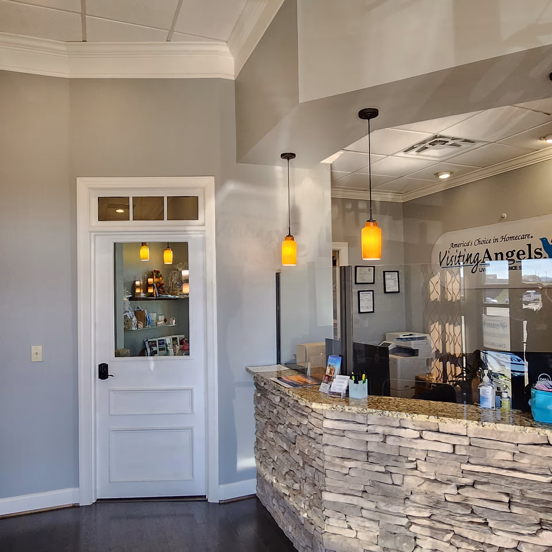 Reception area with stone-front desk, glass divider, and warm pendant lights.