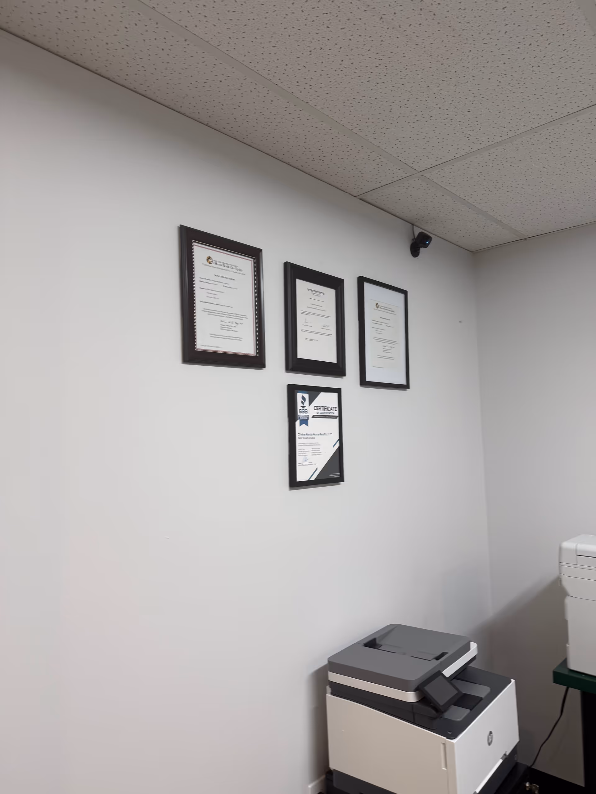 Interior wall with framed certificates and a copier sits nearby.