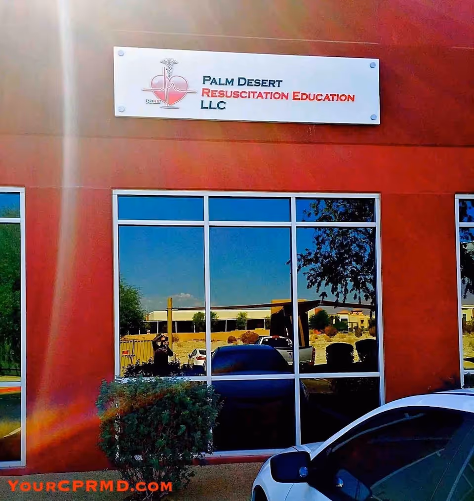 Exterior red wall with a sign reading Palm Desert Resuscitation Education LLC over glass windows.