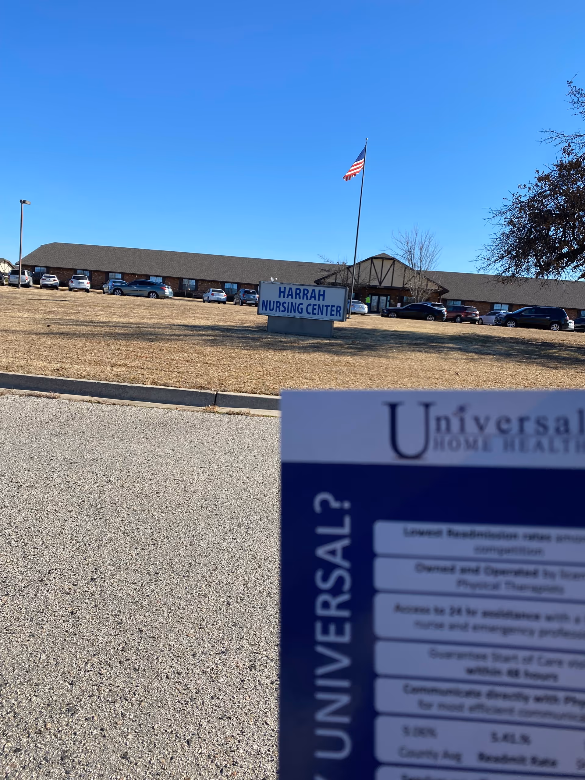 Exterior view of Harrah Nursing Center with American flag and parked cars.