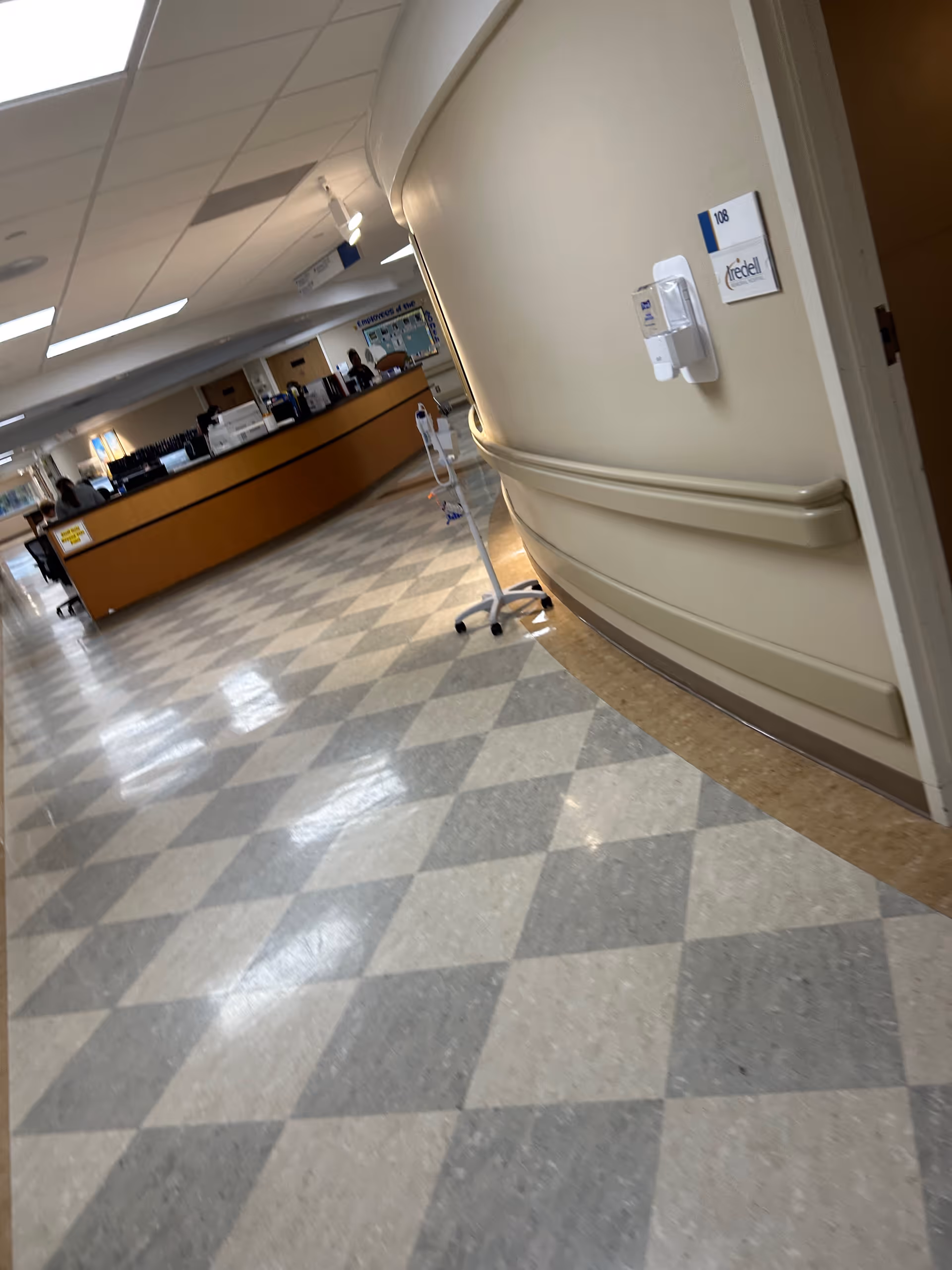 Interior hospital lobby with curved wall, reception desk, and check-in area.