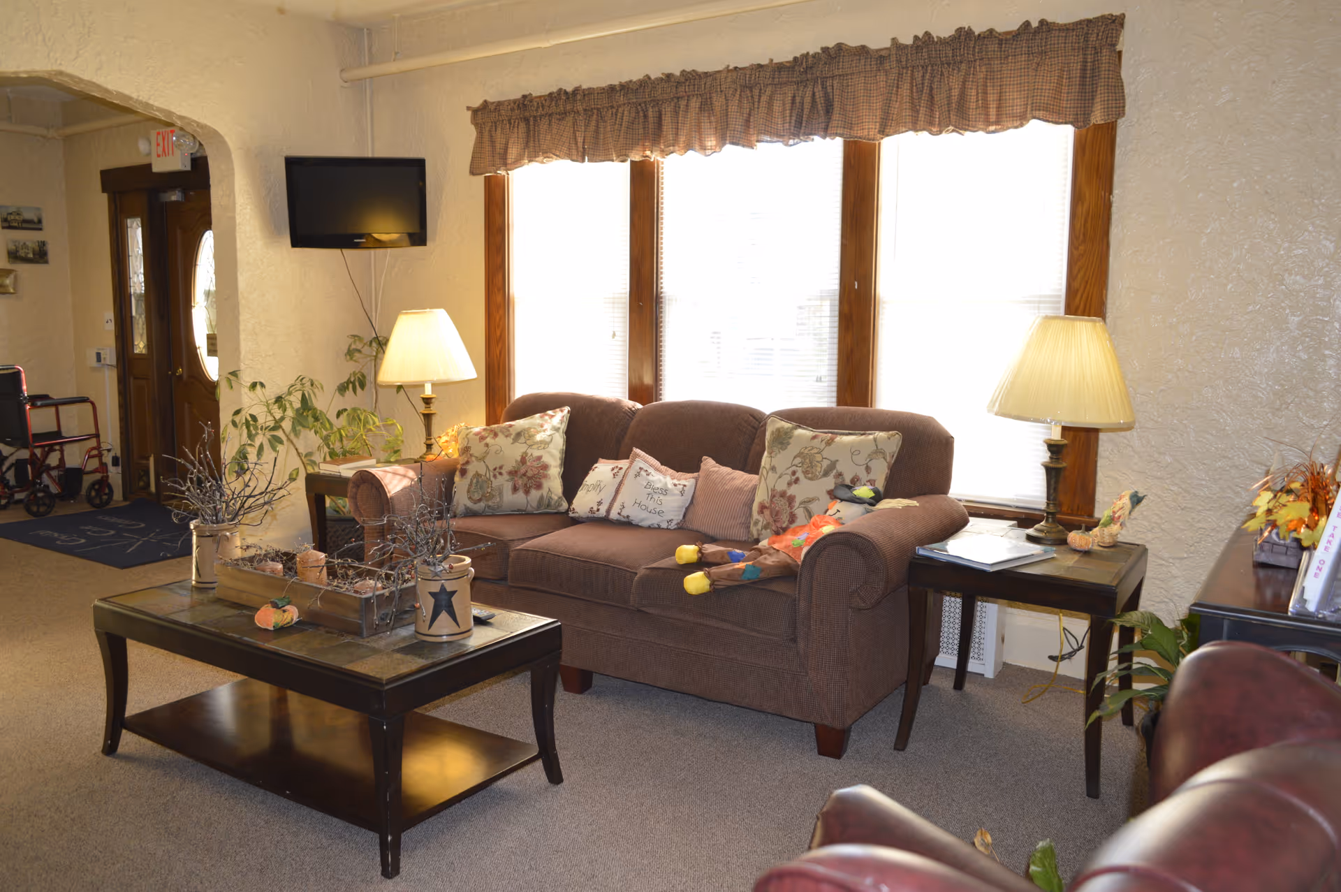 Cozy living room lounge with sofa, lamps, coffee table, large windows, and decor.