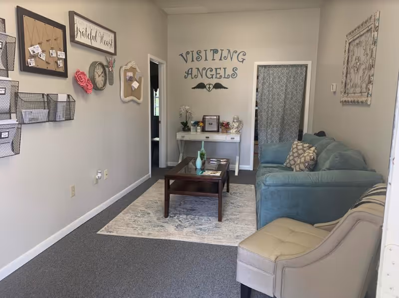Cozy lounge area at Visiting Angels Senior Home Care with sofa, coffee table, rug, and decor.