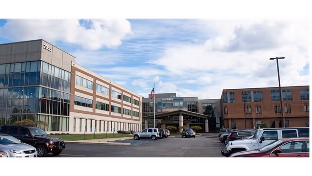 Exterior view of Mercy Health Clermont Hospital with entrance, parking lot, and blue sky.