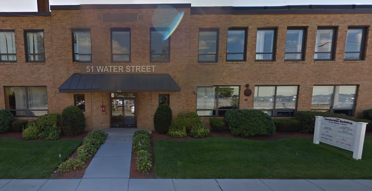 Brick building exterior with entrance labeled 51 Water Street and manicured landscaping.